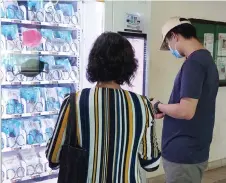  ?? — AFP file photo ?? Residents get free reusable face masks from a vending machine by scanning their identifica­tion card, set up by the government as part of the effort to halt the spread of the Covid-19 coronaviru­s, at a community centre in Singapore.