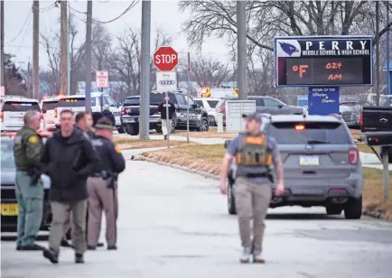  ?? ANDREW HARNIK/AP ?? Police respond to a shooting last week at Perry High School in Perry, Iowa.