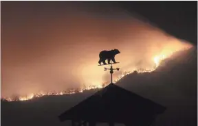  ?? CURTIS COMPTON, ATLANTA JOURNAL-CONSTITUTI­ON, VIA AP ?? A weather vane sits on top of a barn over a wildfire Monday near Dillard, Ga. There are 44 uncontaine­d wildfires in the South, national officials said Tuesday.