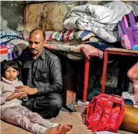  ?? ?? Muhammad Amin, who works as a security guard, sits with his daughters at their home in Lahore