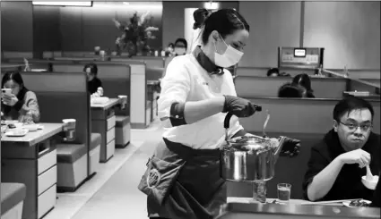  ?? AP PHOTO/FRANK AUGSTEIN ?? In this March 5 photo, a waitress of the Chinese restaurant Hot Pot serves customers in London.