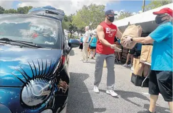  ?? MIKE STOCKER/SOUTH FLORIDA SUN SENTINEL ?? Volunteers load up cars with kosher food Thursday at the Jewish Federation of Broward County in Davie.