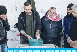  ?? —AFP ?? GAZA CITY: Gabriele Rubini (second left), known as Chef Rubio, cooks with Palestinia­n prisoners at a Hamas-run civilian prison on Tuesday.