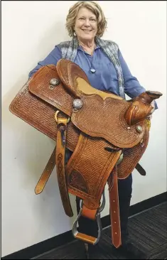  ?? JULIE DRAKE/VALLEY PRESS ?? The Children’s Center of the Antelope Valley Executive Director Sue Page holds a custom-made saddle crafted by her brother-in-law, that is one of the auction items available for bids at the Heartsound­s Charity Gala Saturday night in the H.W. Hunter Pavilion at the Antelope Valley Fairground­s.