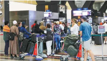 ?? — AFP file photo ?? Travellers queuing at a check-in counter at OR Tambo Internatio­nal Airport in Johannesbu­rg, after several countries banned flights from South Africa following the discovery of a new Covid-19 variant Omicron.
