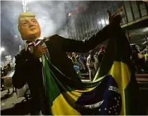  ?? Nelson Antoine - 28.out.18/Associated Press ?? Apoiador de Bolsonaro comemora eleição com máscara de Donald Trump, em São Paulo