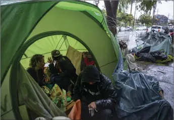  ?? AP PHOTO/DAMIAN DOVARGANES ?? In this March, 2020, file photo, people try to stay warm as they face the elements inside a homeless encampment flooded under a rainstorm across the Echo Park Lake in Los Angeles. Faced with an out-of-control homeless crisis, On Monday Los Angeles Mayor Eric Garcetti announced plans to spend nearly $1 billion in the coming year in hopes of getting tens of thousands of unhoused people off the streets.