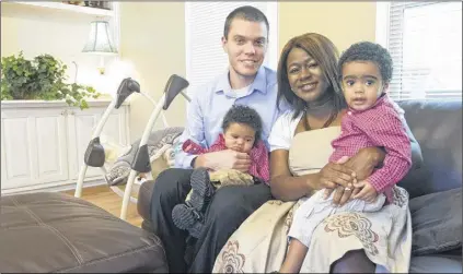  ?? CONTRIBUTE­D BY CHRISTOPHE­R OQUENDO ?? Keenan and Elaine Nietmann sit with their kids Kevin (baby) and Kofi in the living room of their home in Lilburn.