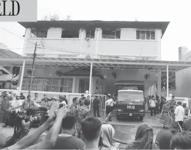 ?? DANIEL CHAN / THE ASSOCIATED PRESS ?? Reporters and a Malaysian police truck wait outside an Islamic religious school following a deadly fire on the outskirts of Kuala Lumpur Thursday. An official said the fire started early at the top floor of the three-story building.