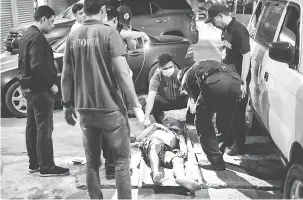  ?? — Gambar AFP ?? BERNASIB MALANG: Pegawai penyiasat memeriksa mayat seorang lelaki selepas polis Filipina membunuh dua orang, termasuk seorang wanita dalam perjalanan ke hospital, yang disangka lelaki bersenjata, di Manila semalam.