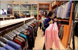  ?? SUN MENG / FOR CHINA DAILY ?? A saleswoman puts shirts on a clothes rack at a Heilan outlet in San Menxia city, Henan province.