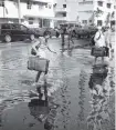  ?? AP ?? Tourists negotiate heavily flooded streets on Miami Beach during king tides.