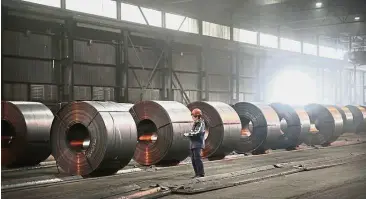  ?? — AFP ?? Ready for shipping: A file picture showing steel coils produced at a steel mill in Indiana being prepared for shipping. Local steel stocks have fallen 18.3% after the US announced proposed tariffs on steel and aluminium imports.