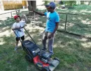  ?? RICH SUGG/KANSAS CITY STAR/TRIBUNE NEWS SERVICE ?? Rodney Smith, right, gives a high five to Erron Blockmon, 9, of Lee’s Summit, Kansas, after they finished mowing a lawn in Overland Park, Kansas.