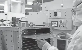  ?? PROVIDED BY INTEL ?? An Intel worker moves a semiconduc­tor panel.
