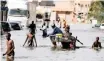  ?? | Reuters ?? RESIDENTS walk through a flooded street after last week’s heavy rains in Keur Massar, Senegal.