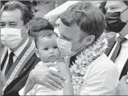  ?? AFP ?? French President Emmanuel Macron holds a baby as he greets residents on Mo’orea Island in French Polynesia.