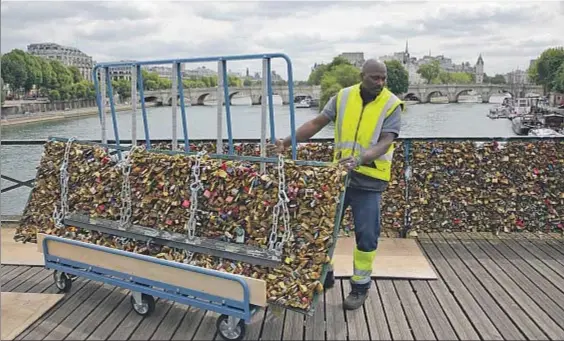  ?? PHILIPPE WOJAZER / REUTERS ?? Efímera eternidad. Un operario municipal retira ayer un panel lleno de candados de labaranda del Pont des
Arts de París