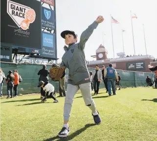  ??  ?? Reid Lafferty of Burlingame gets a feel for what it’s like to play in the big leagues as he throws a baseball on the outfield grass at Oracle Park.