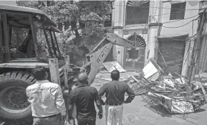  ?? ALTAF QADRI/AP FILE ?? Officials watch as a bulldozer razes the wall of a mosque on April 20 in an area that had recently seen communal violence during a Hindu religious procession in New Delhi’s northwest Jahangirpu­ri neighborho­od.