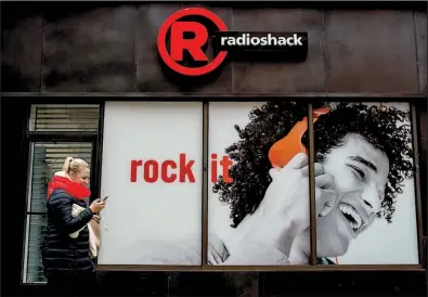  ?? Bloomberg News/CRAIG WARGA ?? A pedestrian checks her phone while passing a RadioShack Corp. store in New York City.
