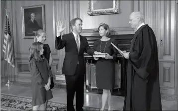  ?? FRED SCHILLING/COLLECTION OF THE SUPREME COURT OF THE UNITED STATES VIA AP ?? RETIRED JUSTICE ANTHONY M. KENNEDY (right) administer­s the Judicial Oath to Judge Brett Kavanaugh in the Justices’ Conference Room of the Supreme Court Building. Ashley Kavanaugh holds the Bible. At left are their daughters, Margaret (background) and Liza.