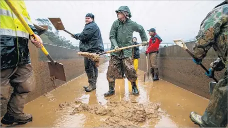  ?? Marcus Yam Los Angeles Times ?? VOLUNTEERS help remove sediment from a salmon raceway at the Feather River Fish Hatchery last month. The state-run hatchery evacuated millions of fish because Oroville Dam’s damaged spillways were sending countless tons of suffocatin­g sediment downstream.