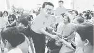  ?? ?? PENGHARGAA­N: Chieng (tengah) mengagihka­n minyak masak kepada salah seorang penerima di Sibu, semalam.