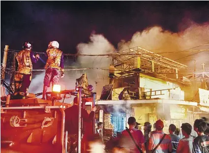  ?? SUNSTAR FOTO / ALEX BADAYOS ?? THIRD-ALARM BLAZE. Residents watch as fire destroys houses on C. Padilla St. in Barangay Duljo-Fatima, Cebu City less than two weeks after the city’s biggest fire struck the barangay on Christmas Day.