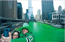  ?? JAMES FOSTER/ASSOCIATED PRESS FILE PHOTO ?? Stacey Peterson and Kevin McGuire take a selfie in front of the green Chicago River to celebrate St. Patrick’s Day in 2018. It was among Irish American communitie­s that the holiday became the celebratio­n it is, from its roots as a more solemn day with a religious observance in Ireland.