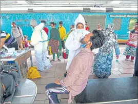  ??  ?? A healthcare worker collects swab sample of a passenger at Dadar station, on Thursday.