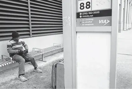  ?? Jerry Lara / Staff photograph­er ?? A man smokes by a VIA Metropolit­an Transit bus stop at St. Mary’s and Martin this month. VIA currently operates 528 buses.