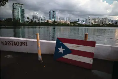  ?? The Associated Press ?? ■ A wooden Puerto Rican flag is displayed Thursday on the dock of the Condado lagoon, where multiple selective blackouts have been recorded in the past days, in San Juan, Puerto Rico. Power outages across the island have surged in recent weeks, with some lasting up to several days.