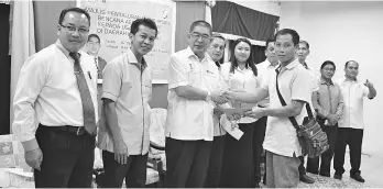  ??  ?? Maximus presenting the RM500 special aid to one of the farmers affected by last year’s prolonged drought at the Farmers Organisati­on Authority Malaysia Kota Marudu Branch office yesterday.