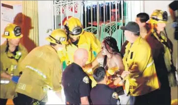  ?? OnScene.TV ?? RESCUE WORKERS assist a woman Tuesday night at the scene of a shooting in Long Beach that left three partygoers dead and nine or more injured. At least one suspect f led the scene and is at large.