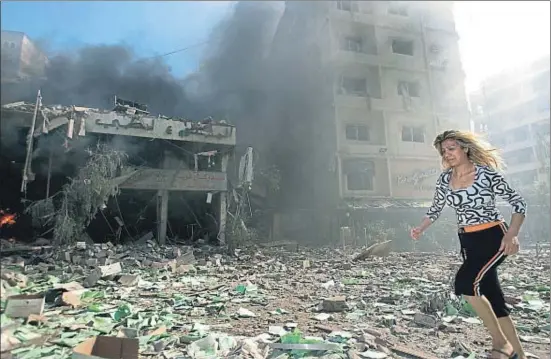  ?? LEFTERIS PITARAKIS / AP ?? Una mujer pasa junto a los escombros causados por un bombardeo israelí en el sur de Beirut en agosto del 2006