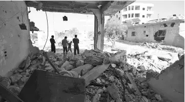  ?? — AFP photo ?? Syrians inspect the damaged of buildings following reported air strikes by pro-government forces in the town of Binnish in Syria’s northweste­rn Idlib province.