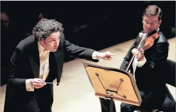  ?? Photograph­s by Jay L. Clendenin Los Angeles Times ?? CONDUCTOR Gustavo Dudamel points past violinist Nathan Cole while leading the Phil in its season opener.