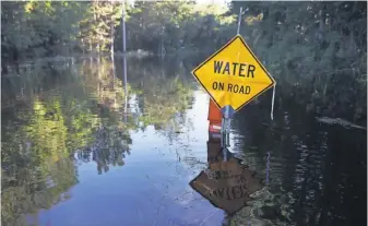  ?? JOE RAEDLE, GETTY IMAGES ?? A road sign seems to state the obvious, treading water next to a washed-out road in Givhans, S.C., on Thursday.