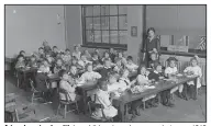  ?? (Library of Congress) ?? A teacher stands with her children in a classroom, between 1919 and 1929.