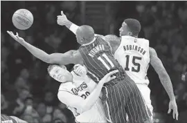  ?? Mark J. Terrill Associated Press ?? BISMACK BIYOMBO of the Orlando Magic reaches over Timofey Mozgov of the Lakers as Thomas Robinson also tries to grab the ball in the first half.