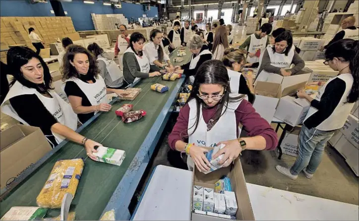  ?? GEMMA MIRALDA ?? Poniendo orden. Los voluntario­s del Banc dels Aliments organizan las cajas de alimentos, en una nave del Parc Logístic de la Zona Franca