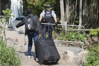  ?? PAUL CHIASSON THE CANADIAN PRESS FILE ?? An asylum seeker is confronted by an RCMP officer as he crosses the border into Canada from the United States last summer near Champlain, N.Y. Canada faces a historic surge in asylum claims, prompting debate on what to do.