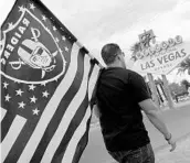  ?? JOHN LOCHER/ASSOCIATED PRESS ?? Matt Gutierrez carries a Raiders flag by a Las Vegas sign after the NFL OKs the team moving to the Nevada city.