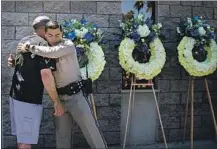  ??  ?? OFFICERS JOSH LONZO, left, and Ramon Duran embrace after placing flowers at the Riverside CHP station Tuesday.