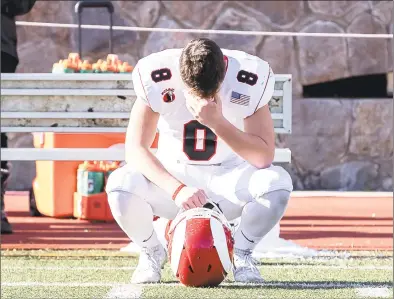  ?? John McCreary / For Hearst Connecticu­t Media ?? Above, Arthur Rakoczy (8), of New Canaan, sits alone on the sideline after a tough state championsh­ip loss after the CIAC Class LL state championsh­ip game between New Canaan and Greenwich on Saturday at Boyle Stadium in Stamford. Right, Greenwich coach John Marinelli gets a hug from his father, New Canaan coach Lou Marinelli, right, after defeating his father’s team 34-0