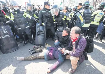  ?? AP ?? An injured supporter of South Korean President Park Geun-hye lies on the ground during a rally opposing her impeachmen­t near the Constituti­onal Court in Seoul yesterday.