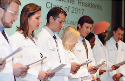  ??  ?? Members of the inaugural class of the internal medicine residency program at the Billings (Mont.) Clinic read the Hippocrati­c oath during their whitecoat ceremony in July.