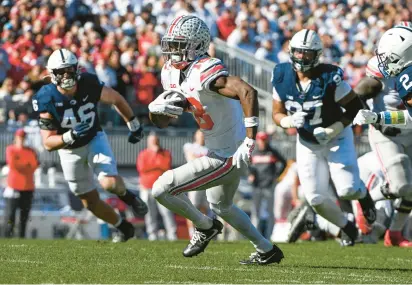  ?? BARRY REEGER/AP ?? Ohio State wide receiver Marvin Harrison Jr. runs away from Penn State defenders Nick Tarburton (46) and PJ Mustipher (97) during the first half of Saturday’s game in State College.