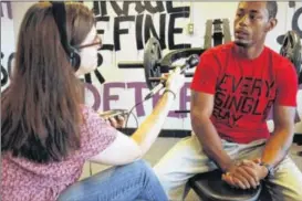  ??  ?? WYSO-FM reporter Juliet Fromholt interviews Jason Shelton at his fitness center in Trotwood as part of the public radio station’s second ReInventio­n Stories project, which looks at how people in the region are making new lives for themselves.